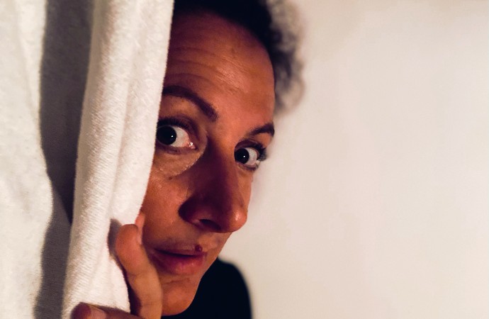 Grusel-Expertin Dora Dämmerlich schaut vorsichtig hinter einem weißen Vorhang hervor. Foto: privat