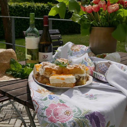 Ein Tisch auf der Terasse des Wirtshauses mit Kuchen und Wein.