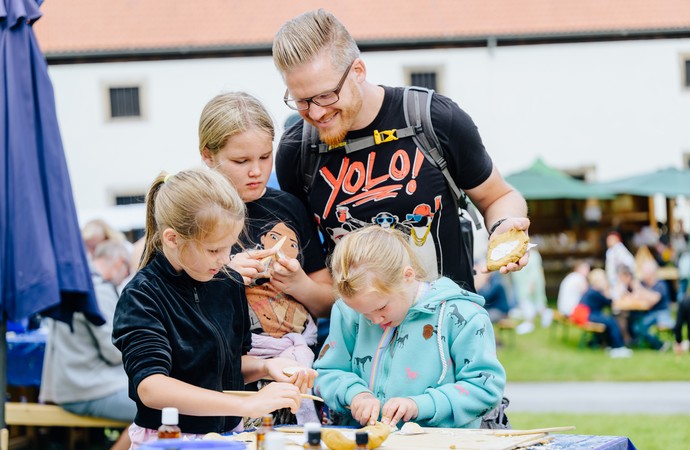 Ein Vater fertigt mit drei Kindern Gipsabdrücke beim Dalheimer Klostermarkt an.