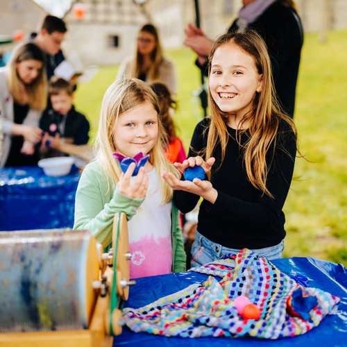 Auf dem Bild sind zwei Mädchen zu sehen, die ihr Selbstgebasteltes präsentieren.