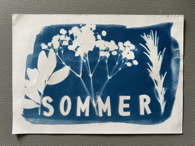 Ein Bild von einem Blaudruck. Mit abgedruckten Blumen und in Großbuchstaben das Wort Sommer.