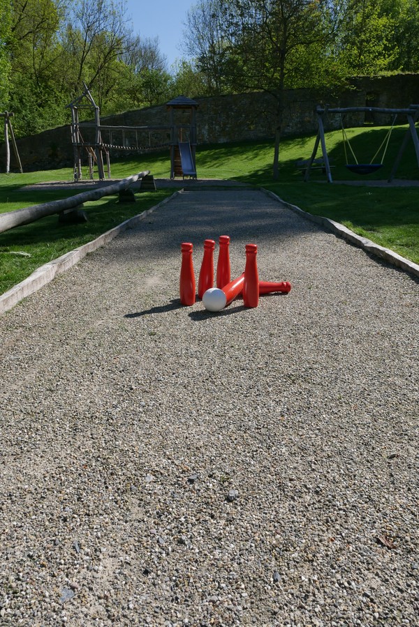 Kegel und eine Kugel liegen auf der Kegelbahn auf dem Spielplatz.
