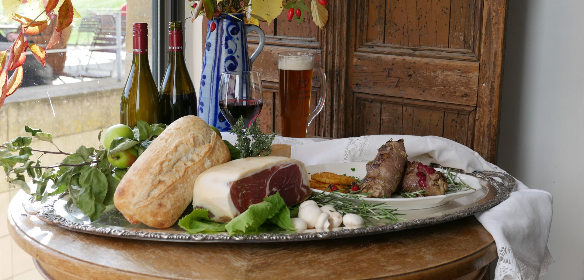 Ein Tisch im Wirtshaus mit Schinken, Brot und anderen Lebensmitteln.
