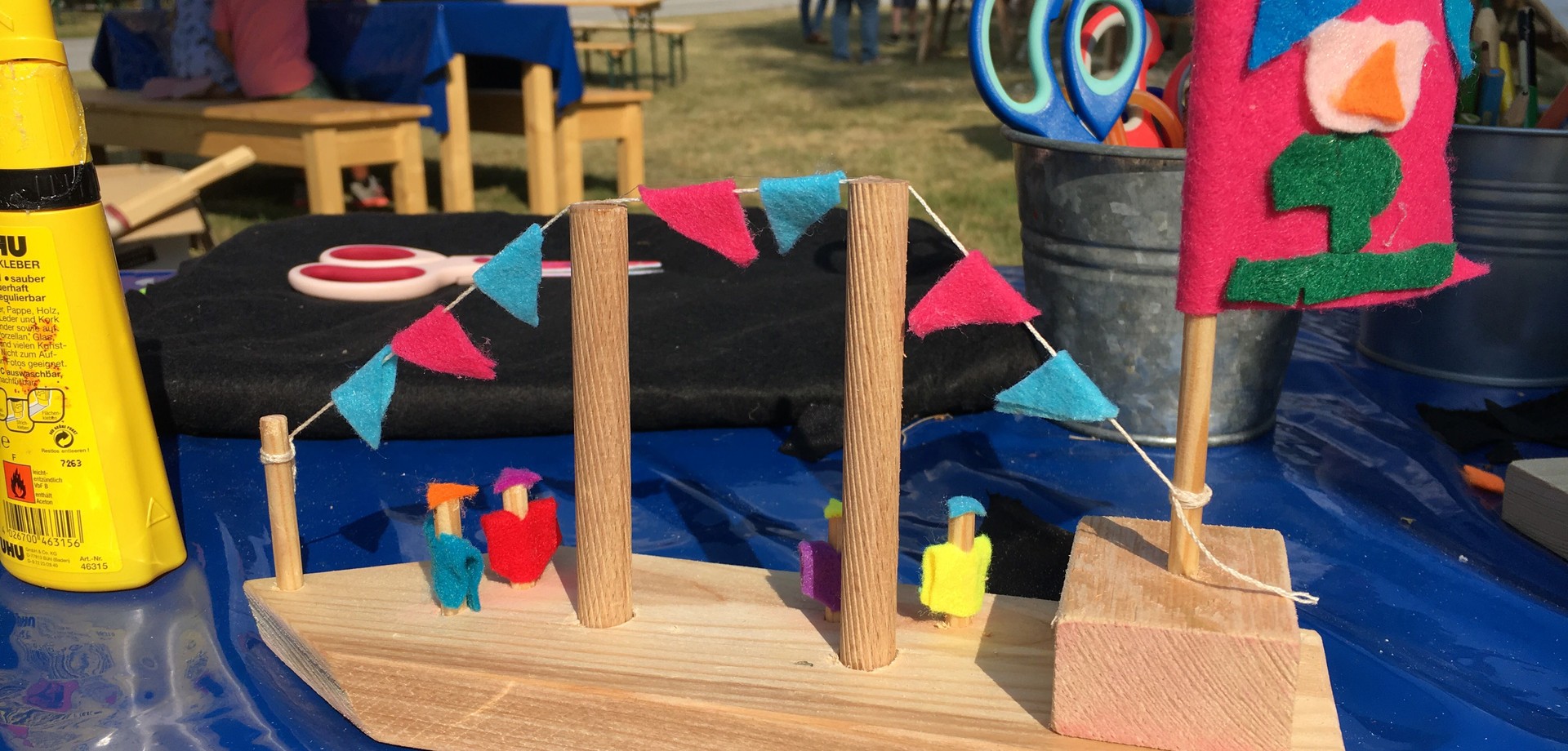 Ein kleines gebasteltes Holzschiffchen steht auf einem Tisch.