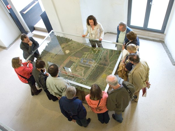 Mehrere Menschen stehen um ein Landschaftsmodell in einer Glasvitrine.