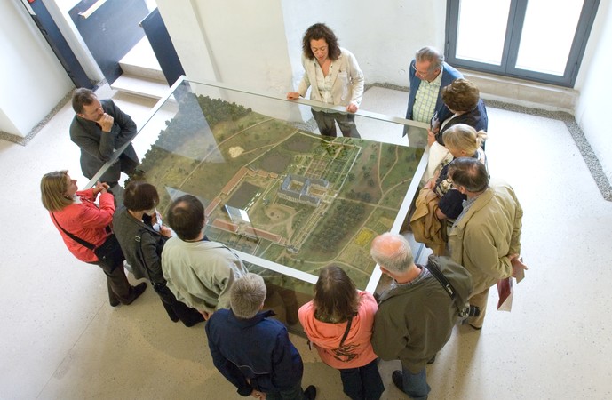 Mehrere Menschen stehen um ein Landschaftsmodell in einer Glasvitrine.