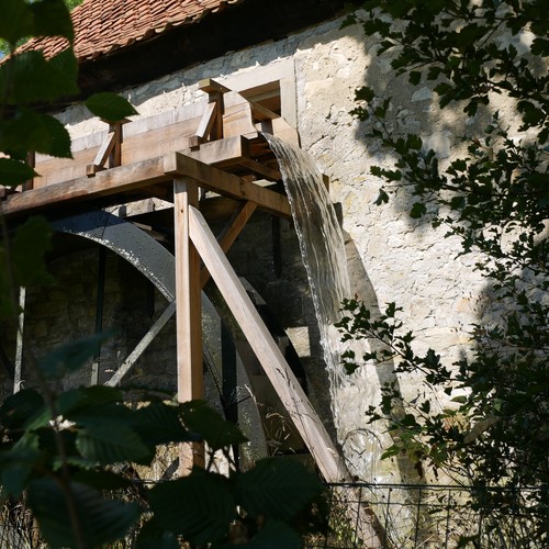 Mühle mit Blick auf das Mühlrad und das fließende Wasser.