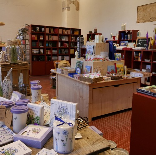 Museumsshop mit Tischen und einem Kartenständer und vielen Verkaufsartikeln.