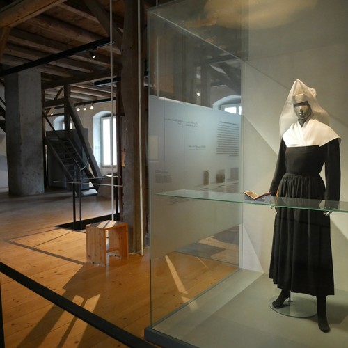 Ein offener Ausstellungsraum mit einer Schaufensterpuppe, die ein klösterliches Gewand trägt.