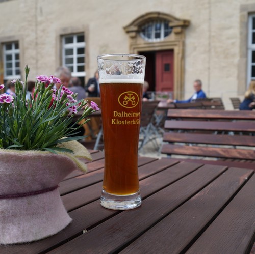 Ein Tisch auf der Terasse des Wirtshauses mit Blumen und einem gefüllten Bierglas.