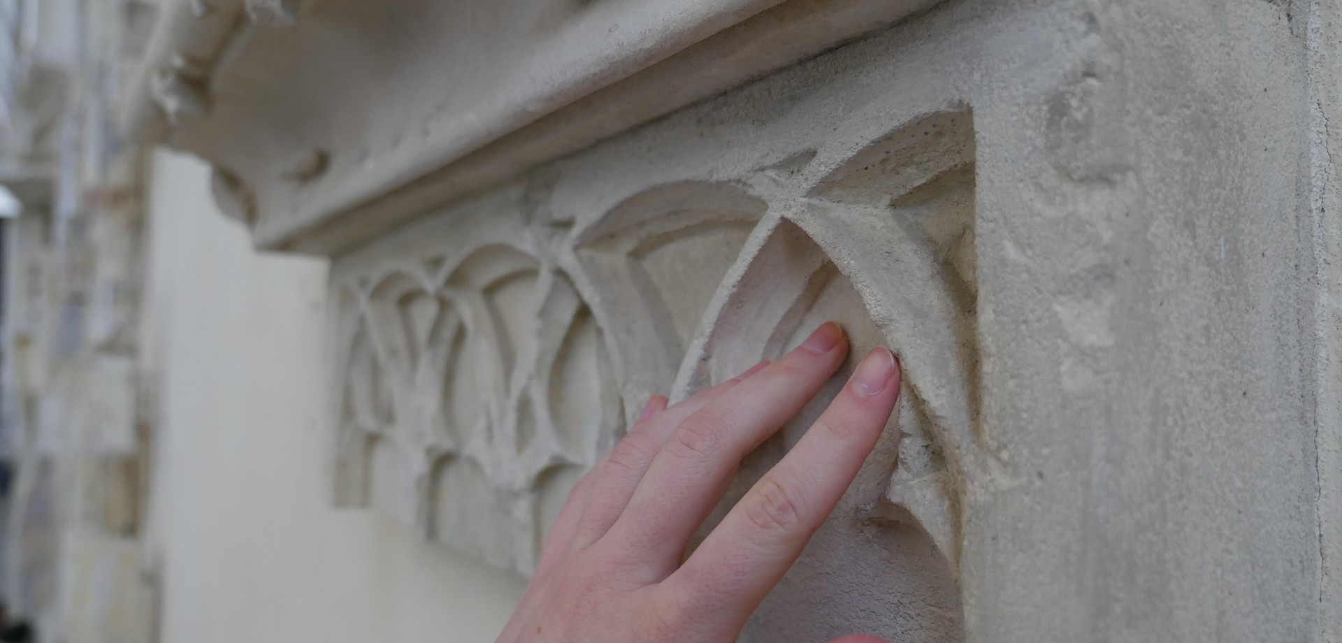 Eine Hand streicht über Sandstein.