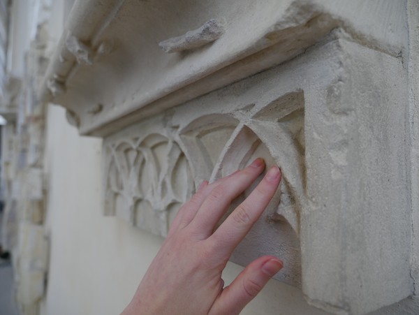 Eine Hand streicht über Sandstein.