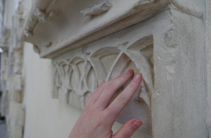 Eine Hand streicht über Sandstein.