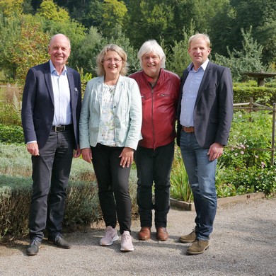 Drei Männer und eine Frau stehen im Garten und schauen fröhlich in die Kamera. Drei Männer und eine Frau stehen im Garten und schauen fröhlich in die Kamera.