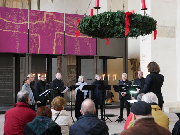 In einer Kirche sitzen Menschen. Unter einem Adventskranz spielen Musiker ihre Instrumente. In einer Kirche sitzen Menschen. Unter einem Adventskranz spielen Musiker ihre Instrumente.