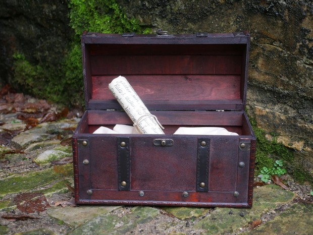 Geöffnete Schatztruhe aus Holz mit Schriftrolle.