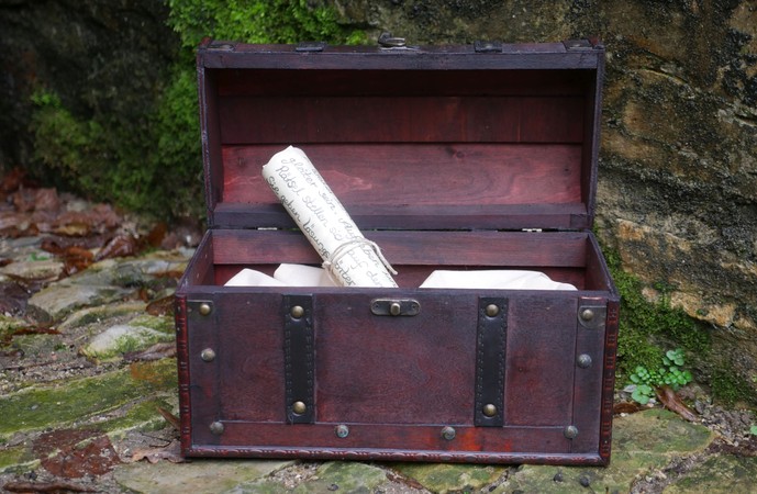 Geöffnete Schatztruhe aus Holz mit Schriftrolle.