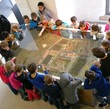 Eine Gruppe Kinder betrachtet ein Landschaftsmodell in einer Glasvitrine.