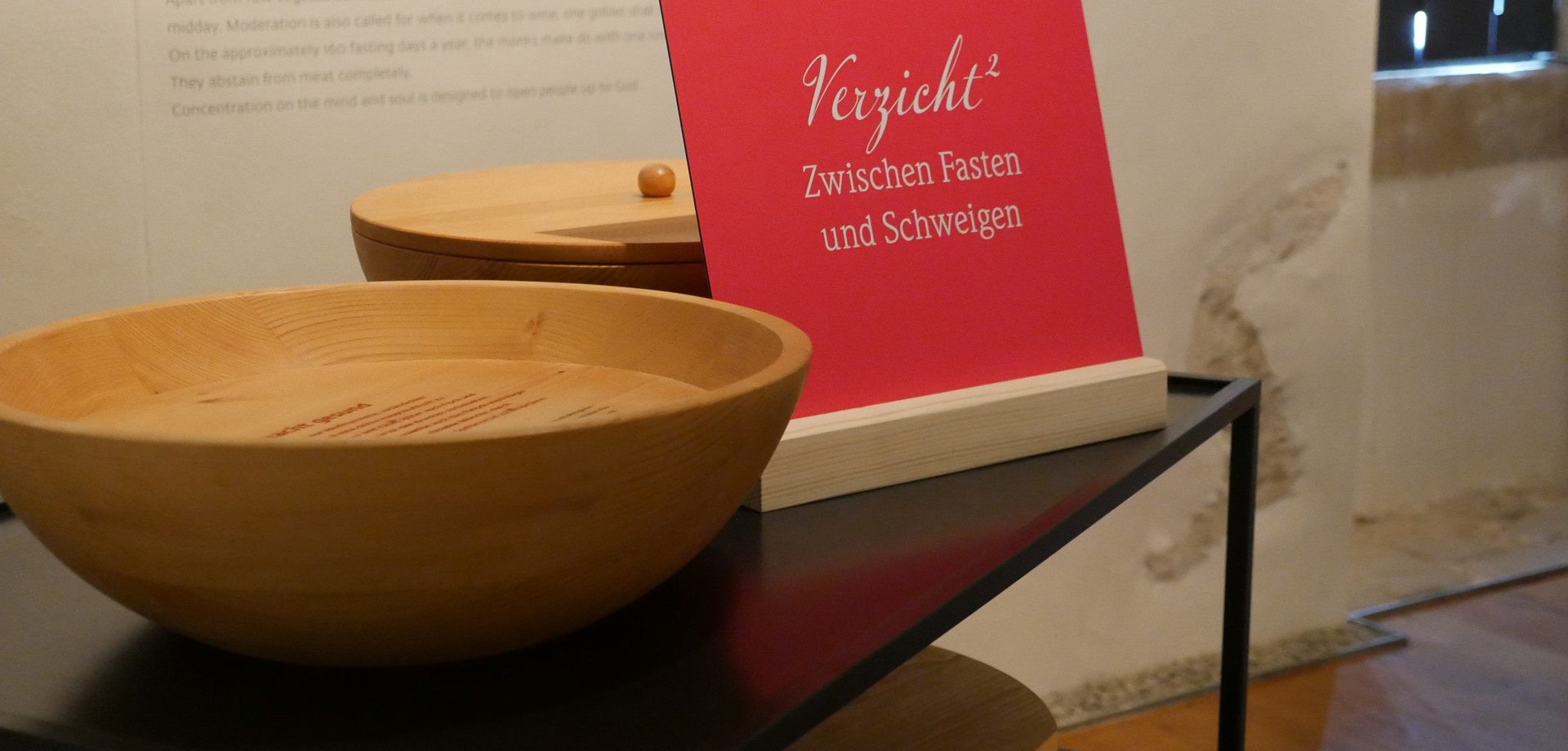 Ein pinkes Schild mit der Aufschrift "Verzicht Hoch zwei" steht auf einem Wagen mit großen hölzernen Schalen.