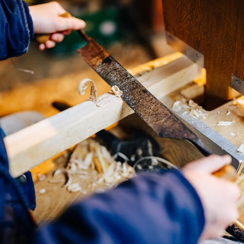 Kinderhände hobeln Holz.