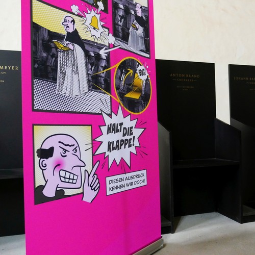Ein Roll up vor dem Chorgestühl erklärt anhand eines Comics woher die Bezeichnung "Halt die Klappe!" kommt.