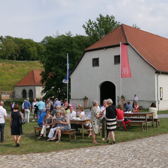 Eine Gruppe von Menschen steht vor dem Neuen Schafstall. (vergrößerte Bildansicht wird geöffnet)