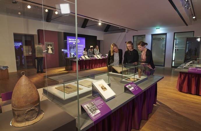 Blick in die Sonderausstellung mit zwei Besuchergruppen, die sich die Exponate anschauen.